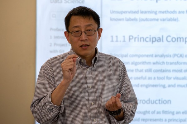 Professor teaching statistics in front of a whiteboard.