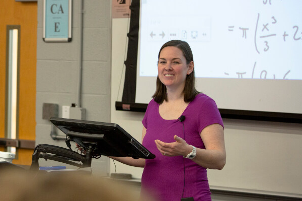 Professor teaching statistics in front of a whiteboard.